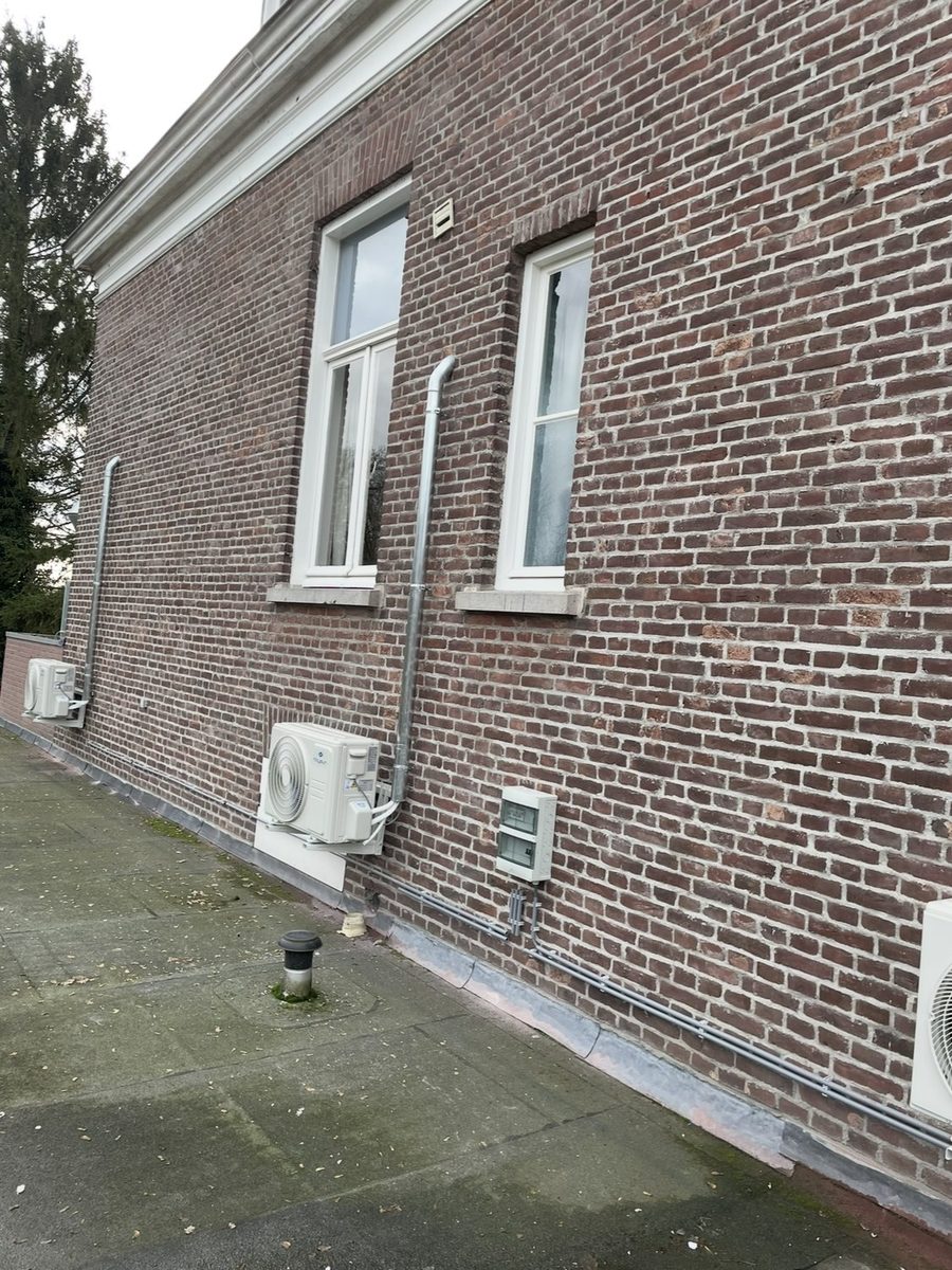 Overzicht van meerdere buitenunits langs een bakstenen gevel